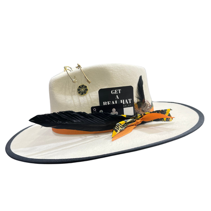 Winter white wide-brimmed hat with decorative feathers and pins on a white background